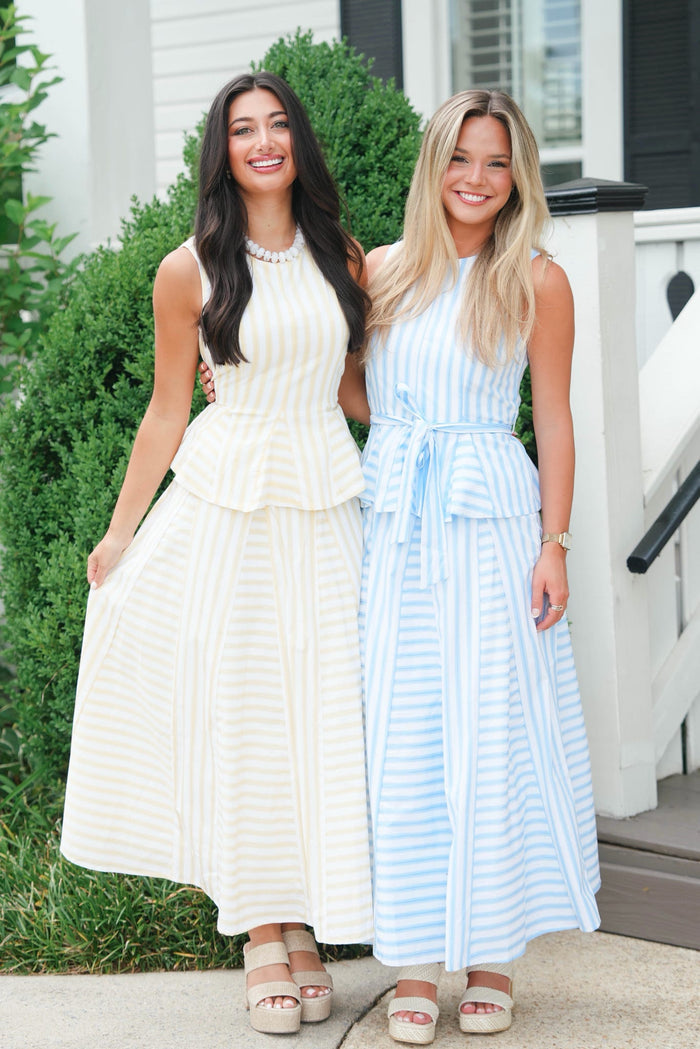 Two women in white and blue dresses standing outdoors.