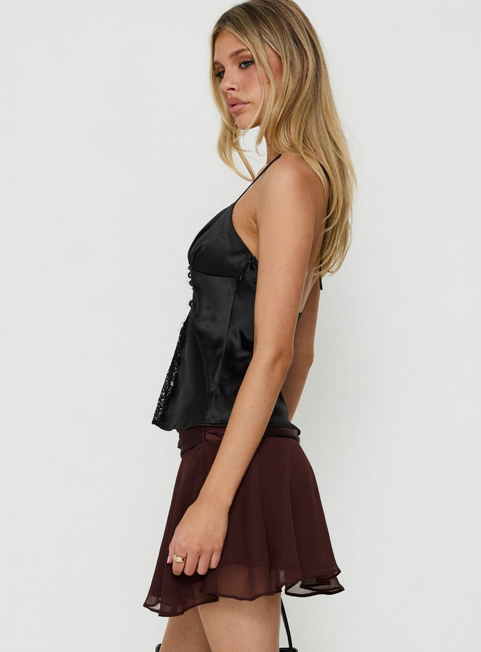 Crafted with asymmetry and flared details, the Emey Asymmetrical Mini Skirt Brown womens-skirts offers a solid maroon design side view of model wearing Princess Polly