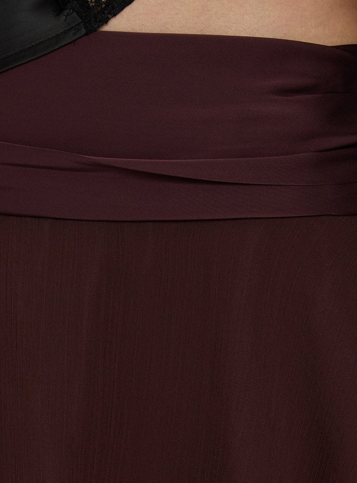 Featuring the Emey Asymmetrical Mini Skirt Brown womens-skirts in solid maroon with flared hem details Princess Polly